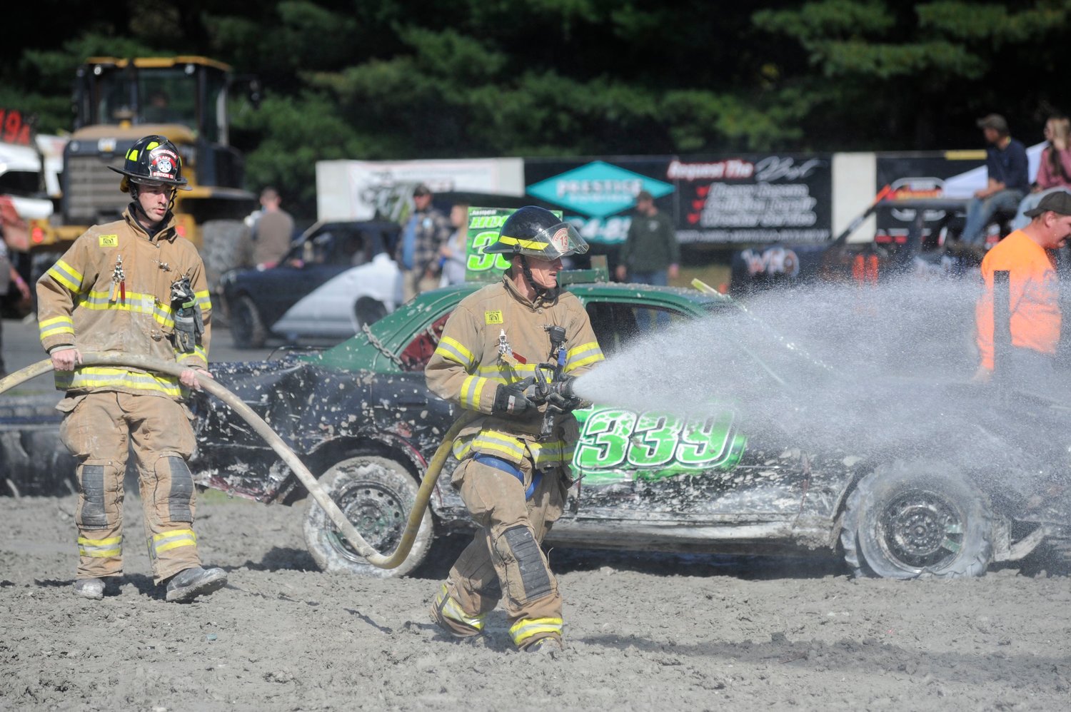 Volunteer fire departments serve their communities in more ways than responding to emergencies. Last year, several local fire departments helped out during a demolition derby at Bethel Motor Speedway by providing safety backup and wetting down the track. Pictured are members of the Kauneonga Lake Fire Department: Ryan Pennell, left, and Bill Pammer with the nozzle.